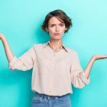 Photo of young funky woman working assistant hold palms pouted lips grimace advantage best product unsure choice isolated on cyan color background.