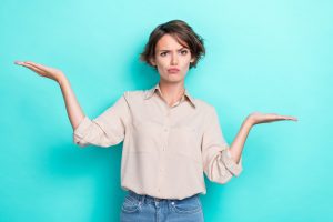 Photo of young funky woman working assistant hold palms pouted lips grimace advantage best product unsure choice isolated on cyan color background.